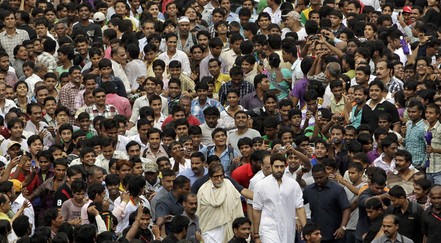 Amitabh Bachchan, center and his son actor Abhishek Bachchan, center right, walk through a sea of fans and mourners to attend the funeral of Rajesh Khanna in Mumbai, India, Thursday, July 19, 2012. 