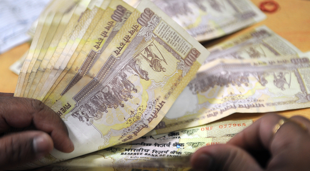 A bank cashier counts Indian Rupee notes at a bank in Mumbai.