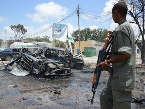An armed man stands guard in Mogadishu on September 7, 2013 at the scene of two deadly explosions earlier the same day